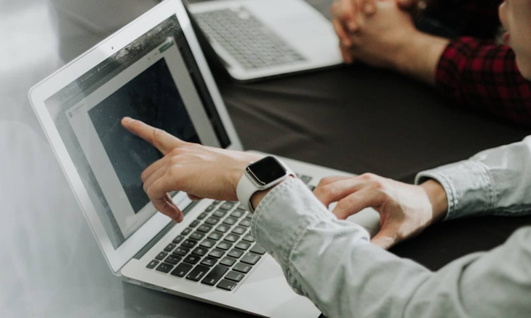 two people sitting at a table with laptops